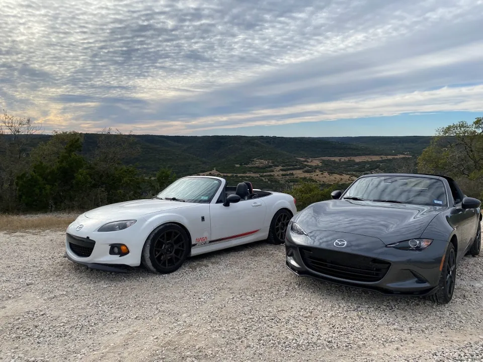 Two Mazda MX-5 Miatas parked at a scenic overlook