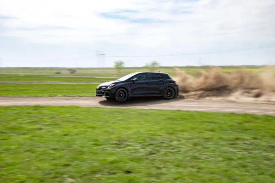 Black Toyota GR Corolla kicking up dust on a dirt road