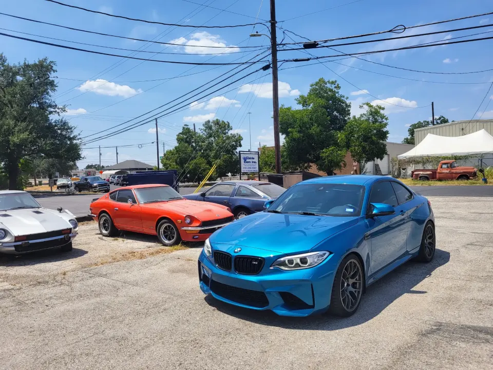 Blue BMW M2 parked beside two classic Datsun Z cars